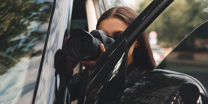 車のフロントドアと車体の隙間からカメラを構える女性