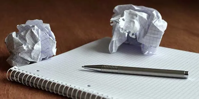 メモ帳とペンとくしゃくしゃに丸められた紙2つ