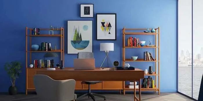 青い壁に机と仕事用具があるオフィス