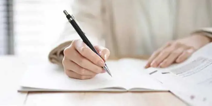 人がペンを持ってノートに書き込んで作業している