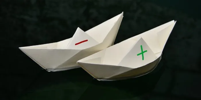 プラスとマイナスが書かれた紙の船の画像