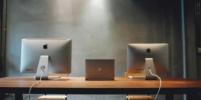 机の上にデスクトップが2つとノートパソコンが1つ